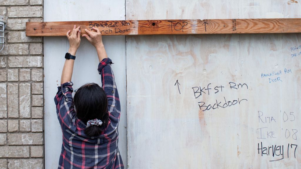 A woman braces a door 