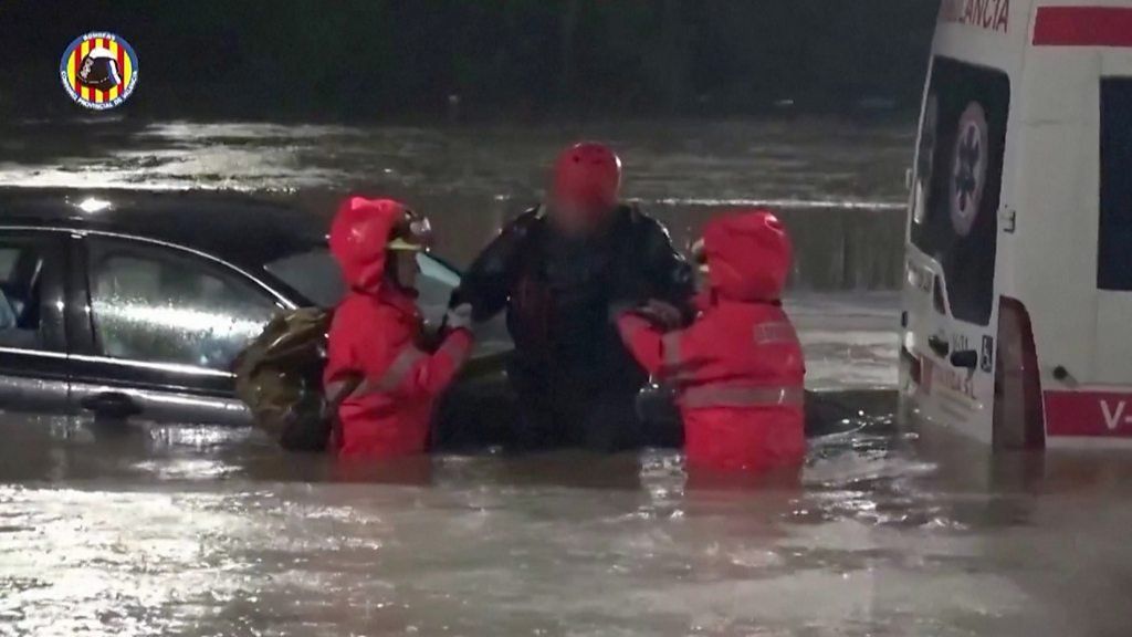 Person being rescued by fire firefighters, from car semi-submerged by water