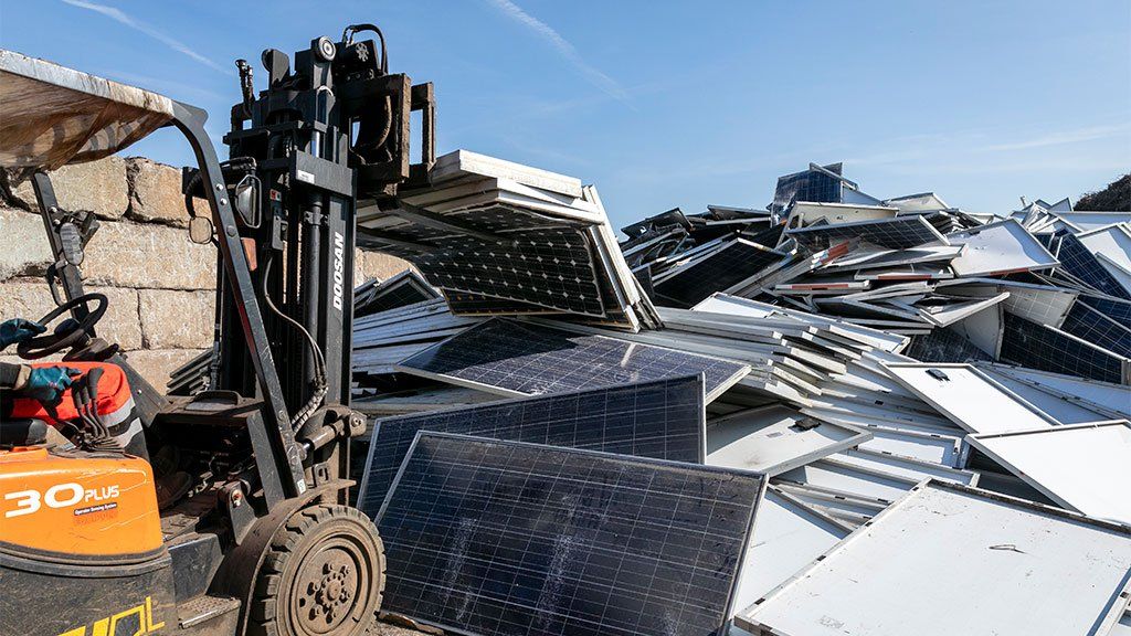 A fork-lift drops solar panels in a heap