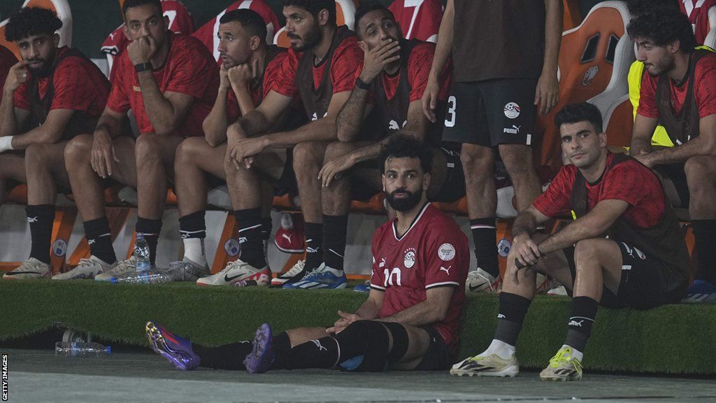 Mohamed Salah sits in front of the Egypt dugout after being forced off during their game against Ghana