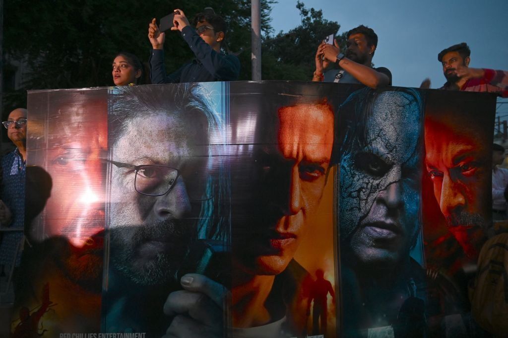 Fans of Indian actor Shahrukh Khan line up, holding images of him and taking photos