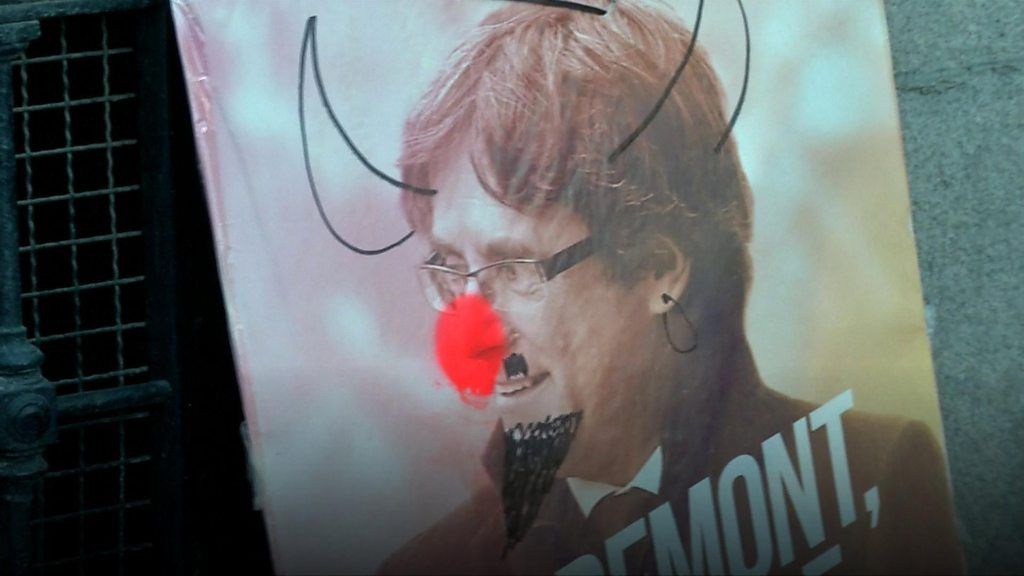 A poster shows Carles Puigdemont, Catalan independence leader, with devil horns drawn on his photo