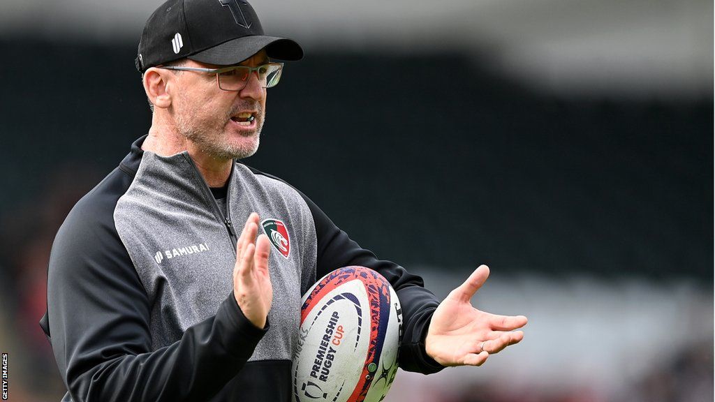 Leicester Tigers head coach claps his hands with the ball tucked under his arm