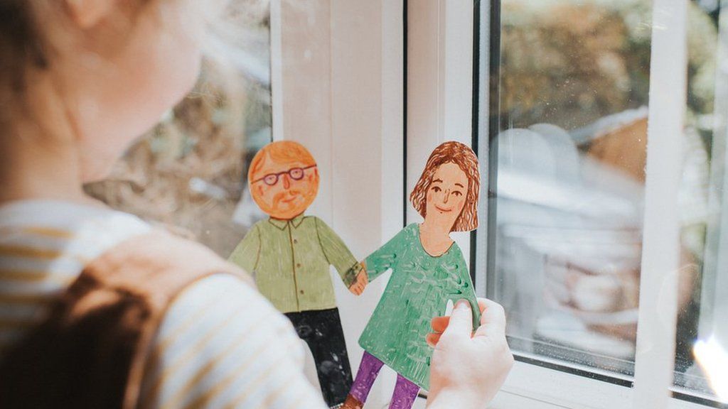 Young girl holding paper dolls of mum and dad