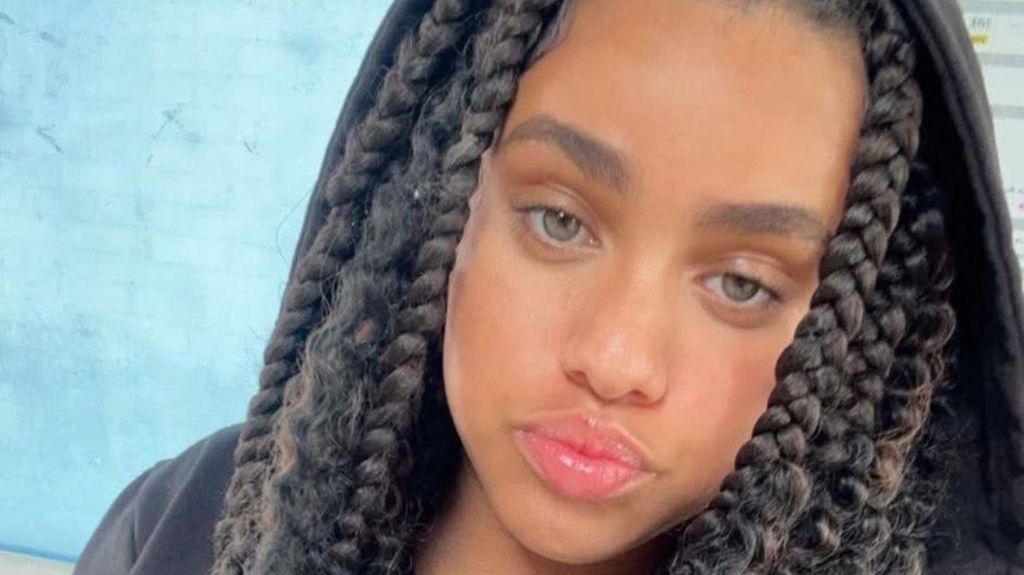 Emily in a black hoodie. She has her hair braided. 