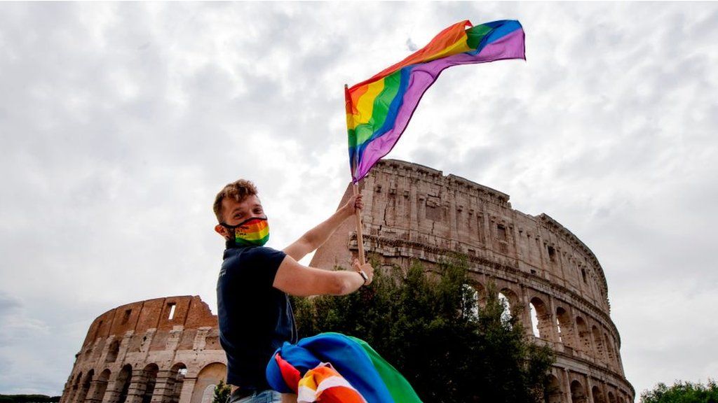 A man waves a Rainbow Flag past the Coliseum monument on 13 June, 2020