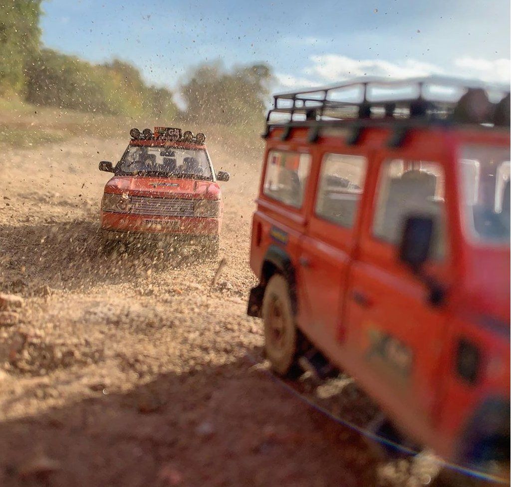 Red model Land Rovers driving along dirt track