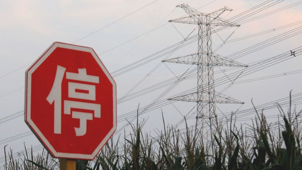 A 'Stop' sign in Chinese next to an electricity pylon in Beijing, China.