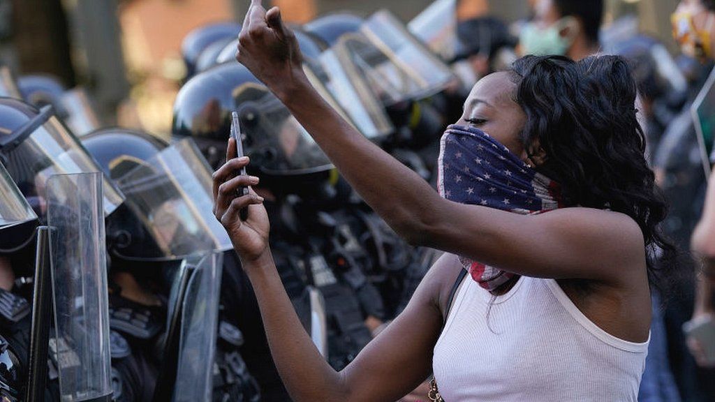 Woman with mobile phone in front of police lines at US demo