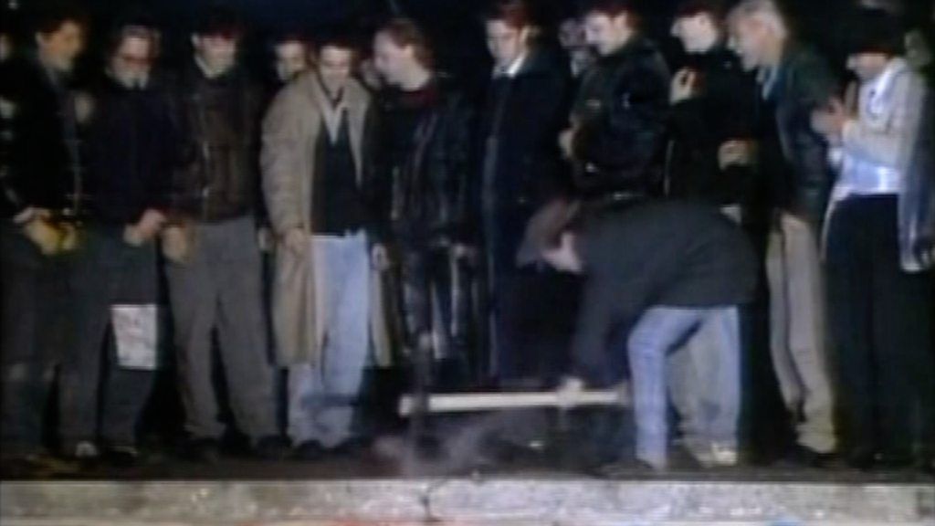 Man trying to break the Berlin Wall with a pickaxe
