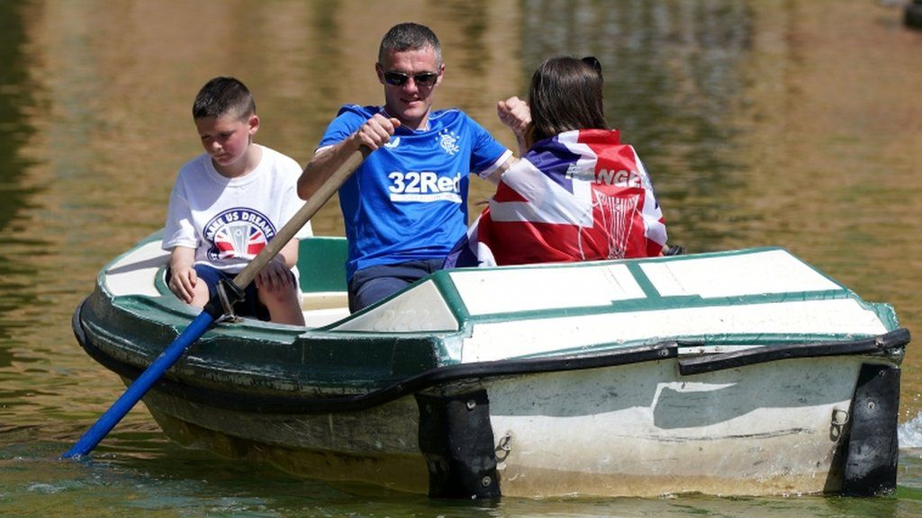 A Rangers fan rows a bat around a a lake in Seville