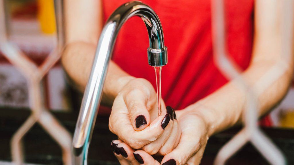A woman washing her hands at a tap