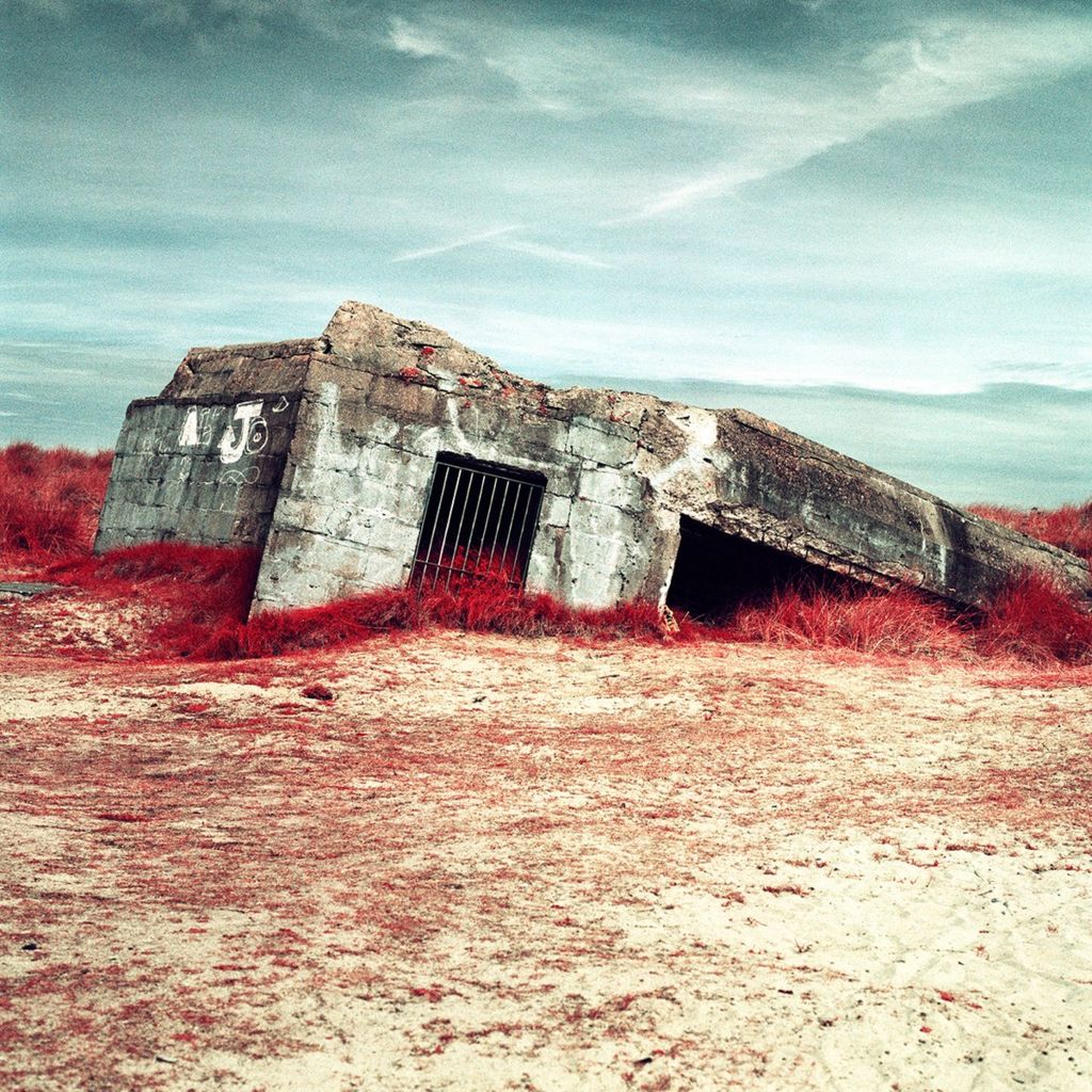 Infrared photograph of a bunker, surrounded by plants and sand