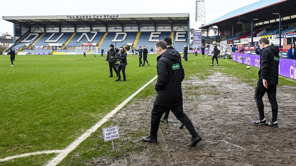 Officials inspect the waterlogged Dens Park pitch before calling off the Rangers game last month