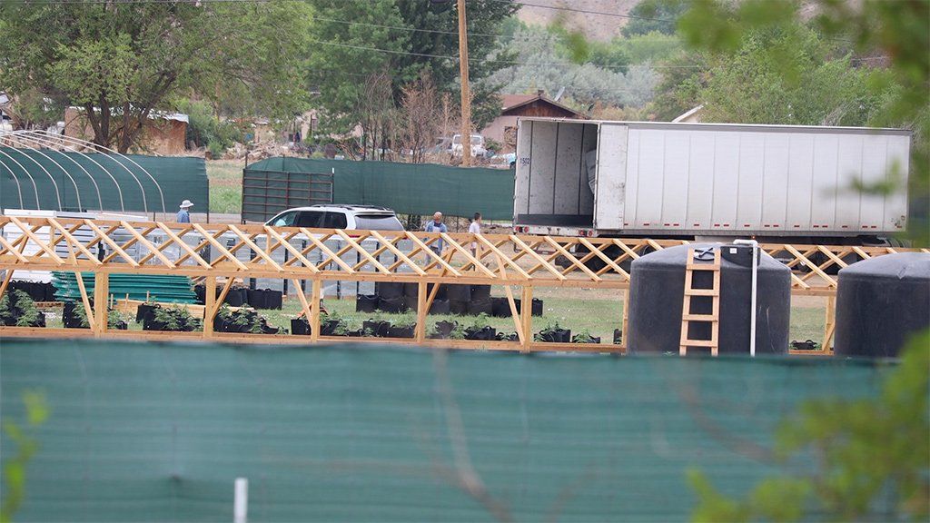 At a cannabis farm near Bea Redfeather's property, workers unload tools from a truck. The farm also has a few septic tanks and a new structure for cannabis green houses