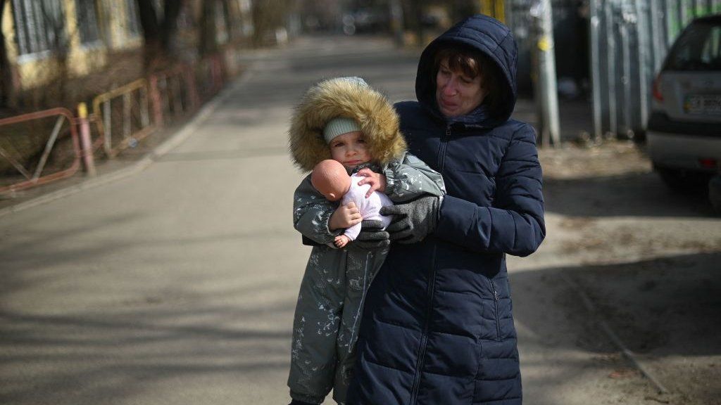 A woman carrying a child walks in east Kyiv, on February 23, 2022.