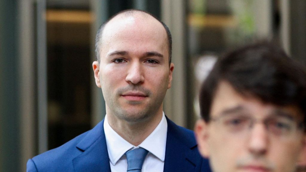 Greg Brockman, an executive and co-founder of OpenAI, walking away from a courtouse entrance wearing a blue suit and neck tie with a white dress shirt. 