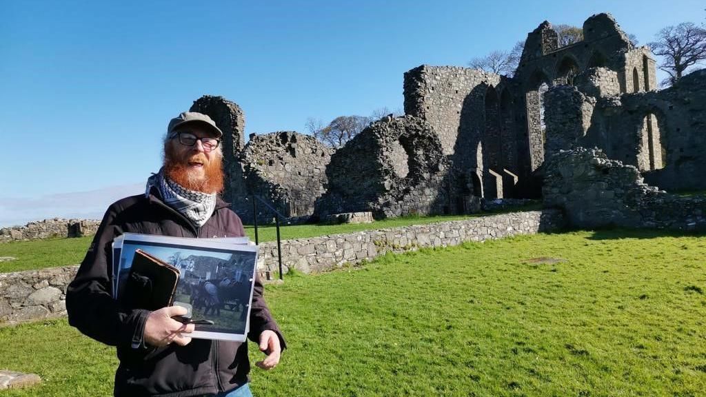 Ginger man standing in front of abbey ruins
