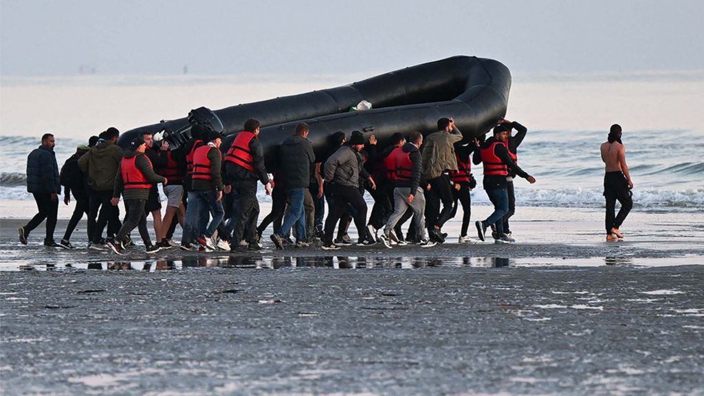 Мигранты несут лодку к воде, прежде чем попытаться нелегально пересечь Ла-Манш в Великобританию, июль 2022 г.