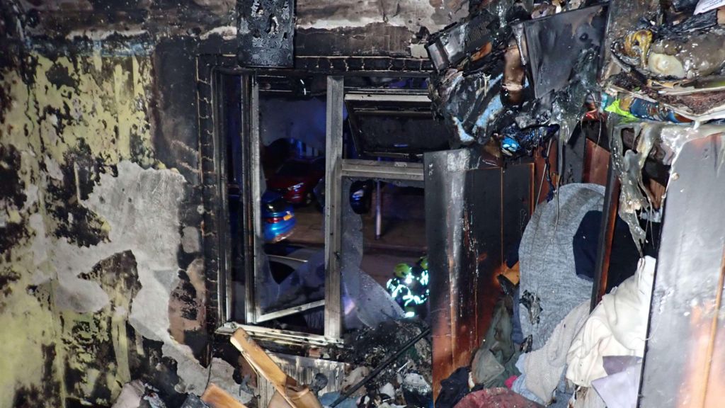 Room devastated by fire showing debris and what looks like a window.