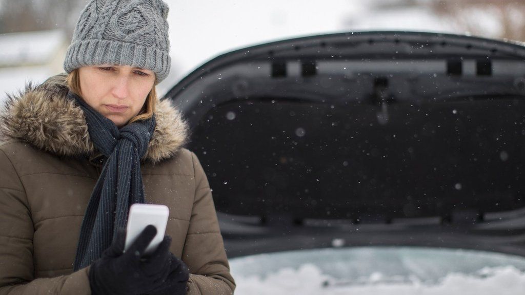 A woman looks pensive after breaking down in the snow