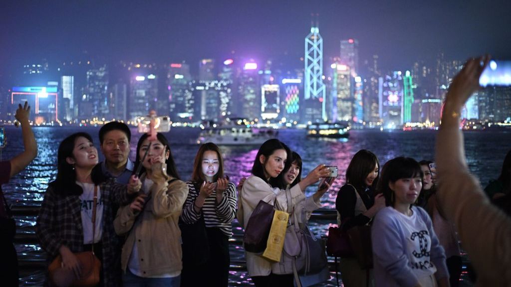 People taking selfies by Hong Kong harbour.
