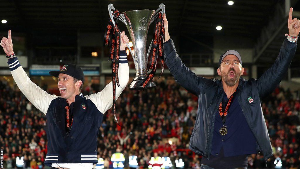Hollywood stars Rob McElhenney and Ryan Reynolds hold the National League trophy after Wrexham won the title