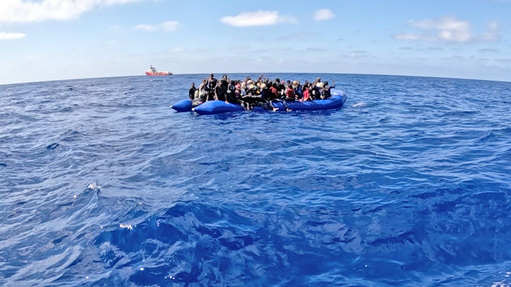 Blue rubber boat full of migrants in the middle of the Mediterranean