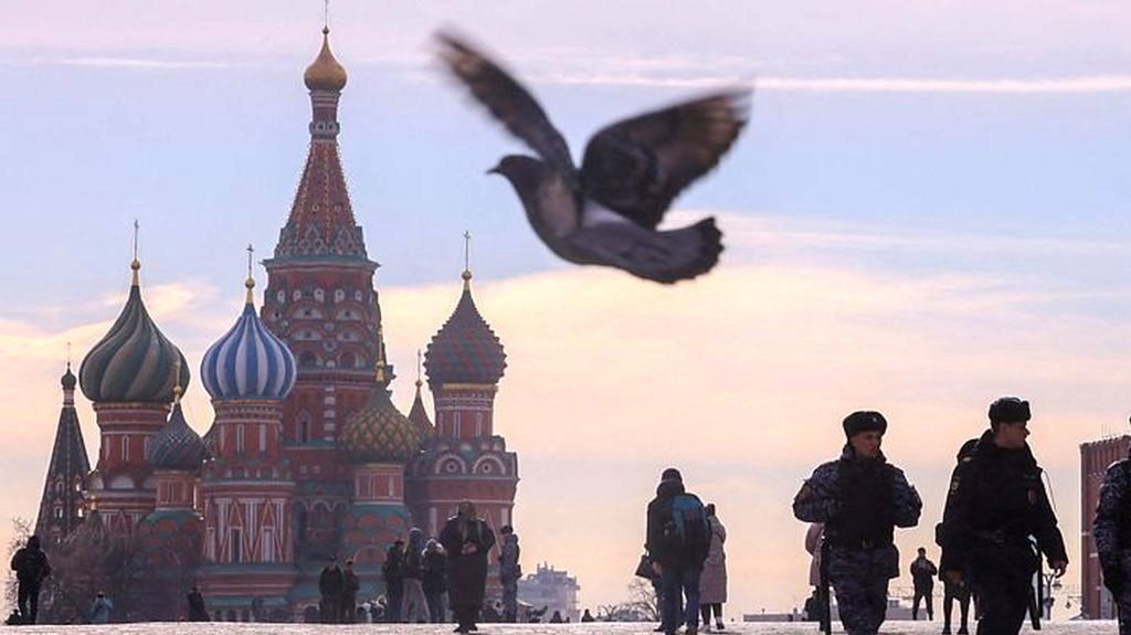 Russian law enforcement walk in red square, with St Basil's Cathedral and the Kremlin visible behind them