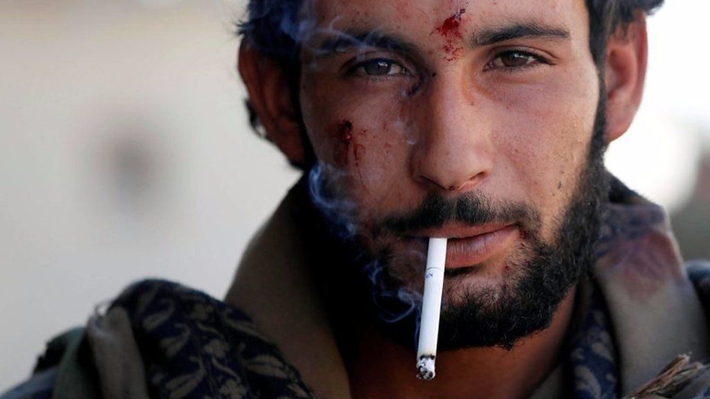 A member of the Syrian Defence Forces smokes a cigarette