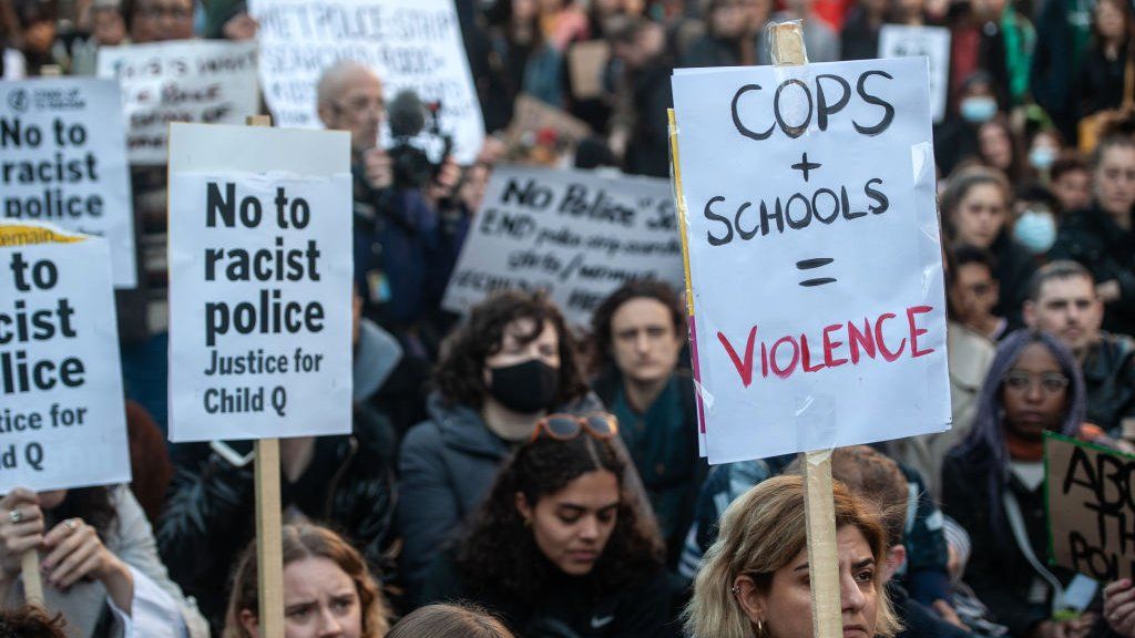 People hold placards protesting against police who strip-searched a 15-year-old black girl