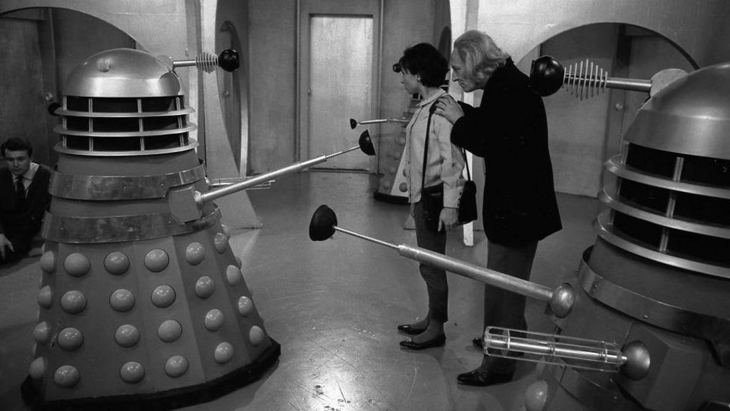 William Hartnell as Dr Who, Carole Ann Ford as Susan Foreman and three Daleks, in a black-and-white image from Doctor Who in 1963