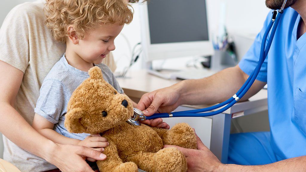 A doctor puts a stethoscope on a child's teddy bear