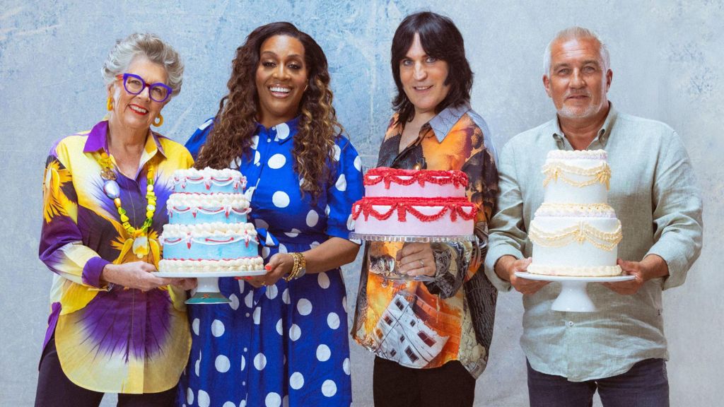 Prue Leith, Alison Hammond, Noel Fielding and Paul Hollywood posing together and holding up large colourful cakes in a publicity photo