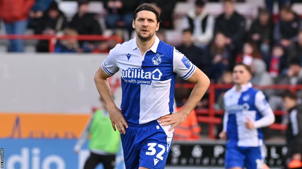 George Friend stands with his hands on his hips on the pitch during a Bristol Rovers game