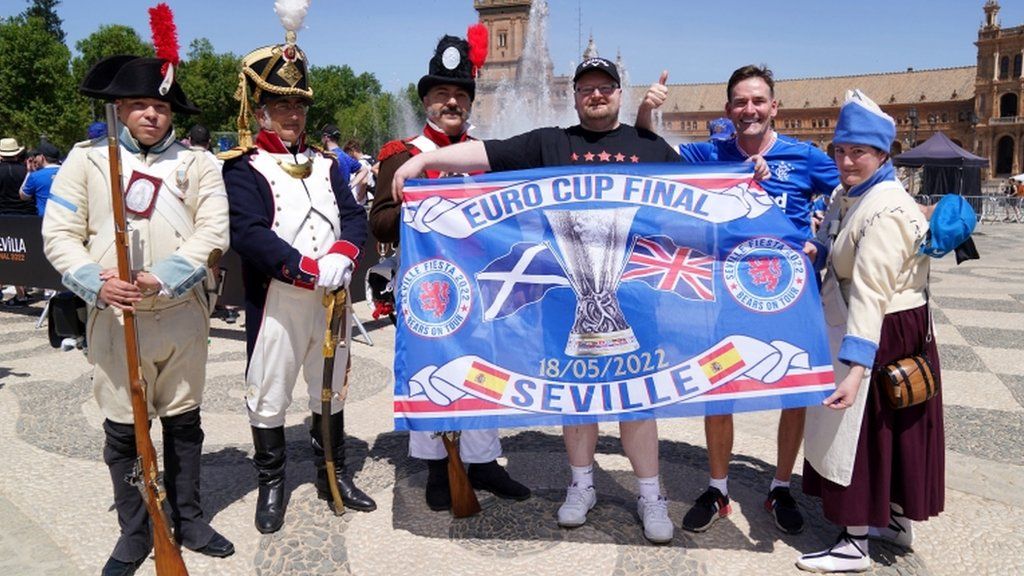 Rangers fans pose with locals in old military outfits in Seville's Plaza de Espana