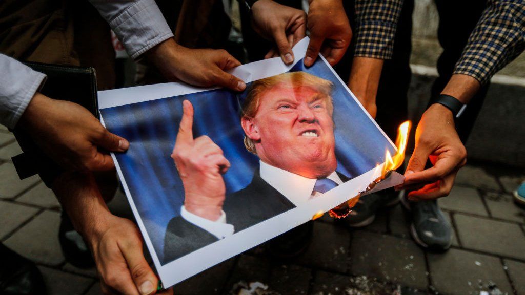 protesters burn a picture of Trump