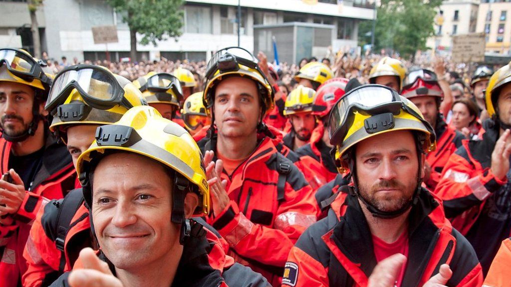 Firefighters joined the crowds in solidarity while Spanish police look on.