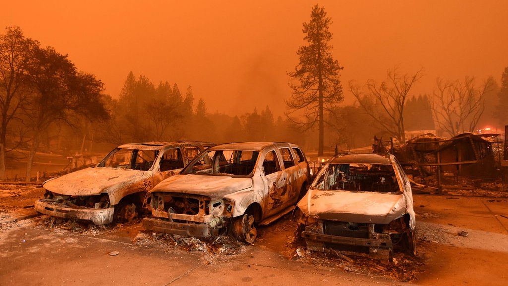 Burnt out cars against smoky, red sky