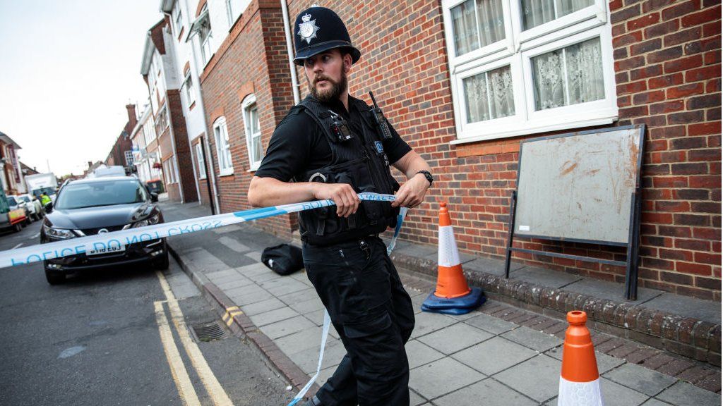 Officer fixes police tape across a Salisbury street