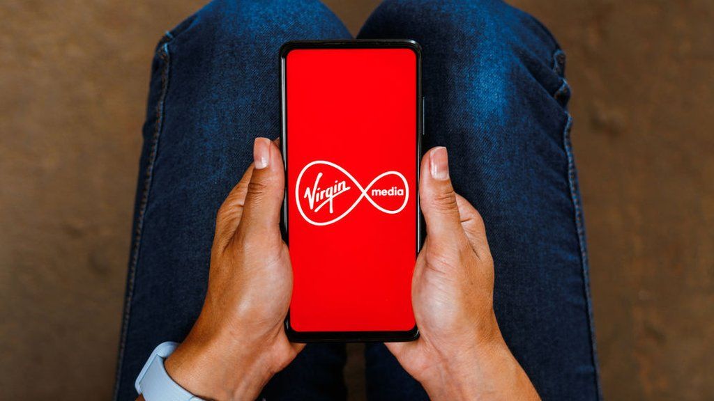A stock image of a phone displaying the Virgin Media logo
