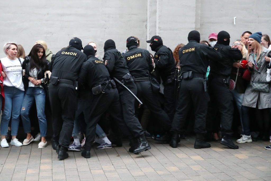 Riot police grab people in order to detain them, from a crowd of women on 8 September