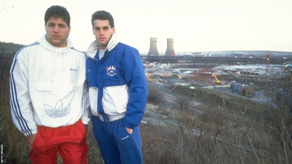 Tony Meola and John Harkes standing on a hill overlooking Sheffield's Tinsley Towers
