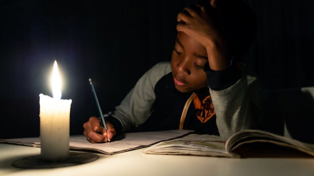 A child doing his homework by candlelight in Harare, Zimbabwe - June 2019