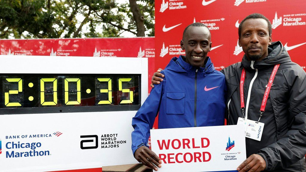Kelvin Kiptum and his coach Gervais Hakizimana pose with a world record sign