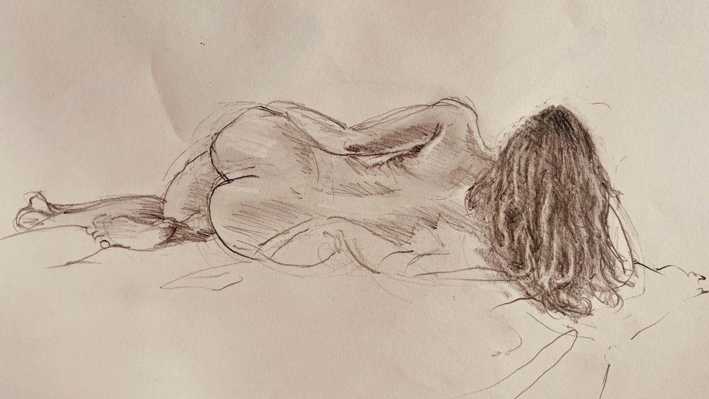 A charcoal sketch of Hollie lying on a blanket as she poses for a life drawing class.