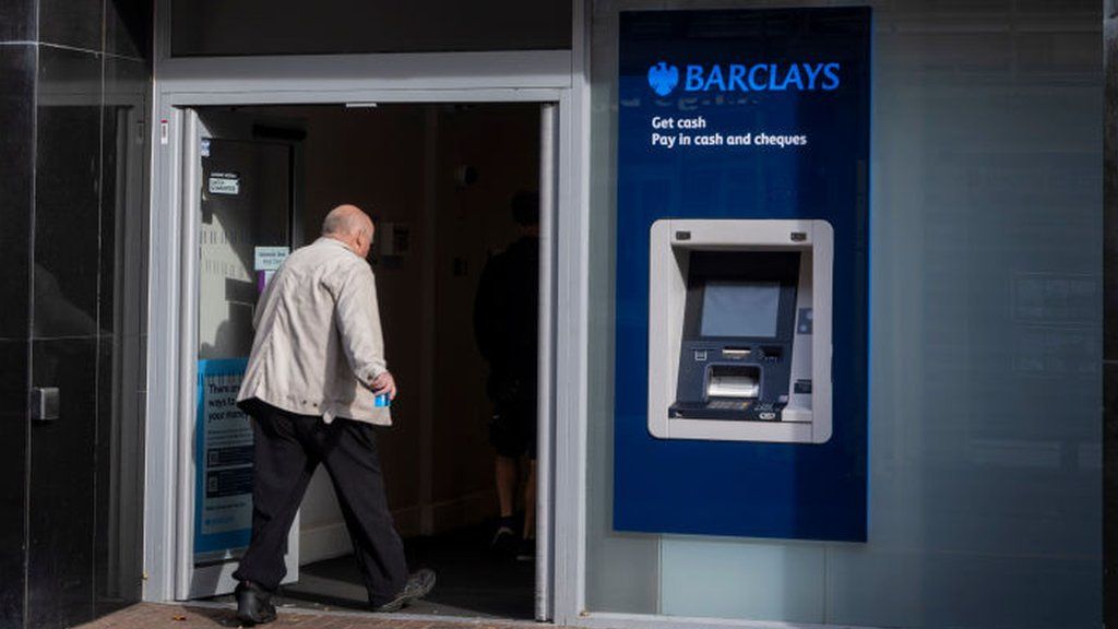 Man walking into a Barclays bank branch