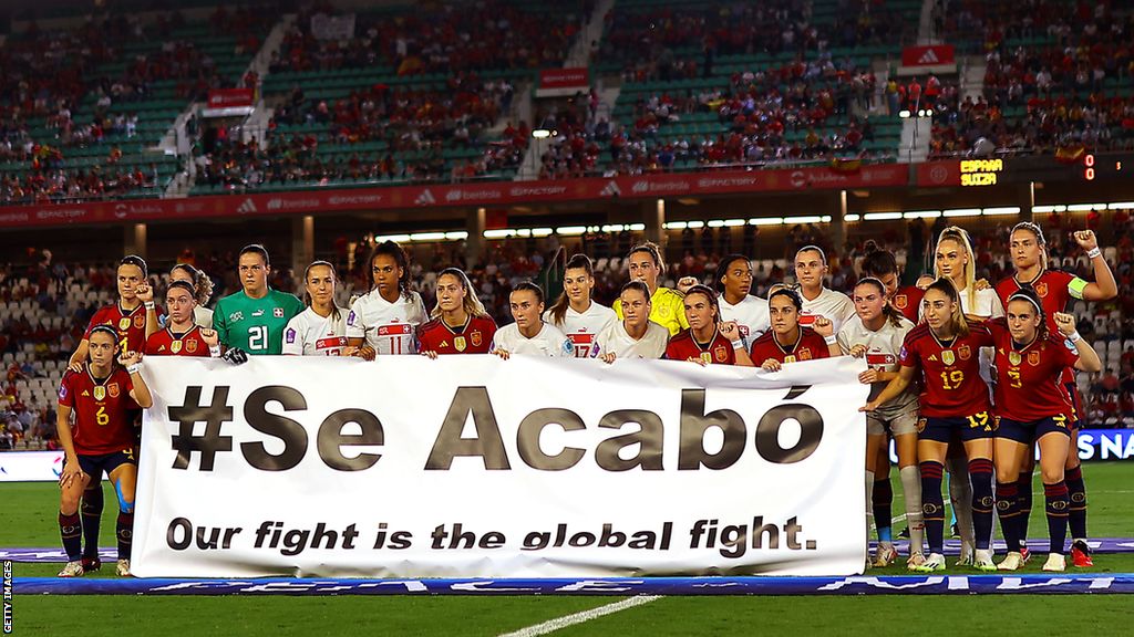 Spain and Switzerland players hold a banner reading "se acabo" which translates to English as "it's over", a phrase used on social media amid the scandal