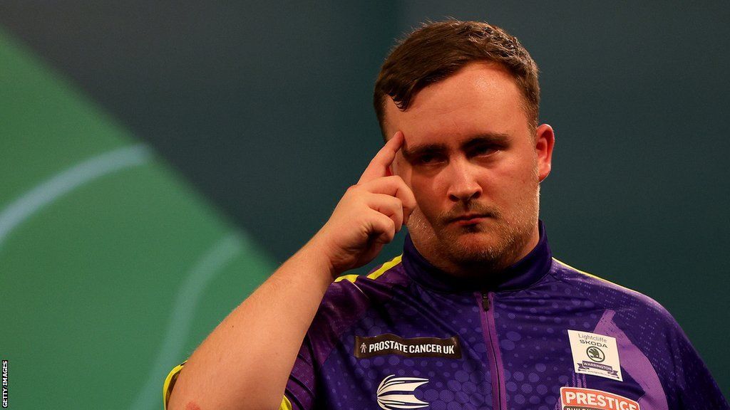 Luke Littler points to his forehead during a match at the 2023-24 PDC Darts World Championship