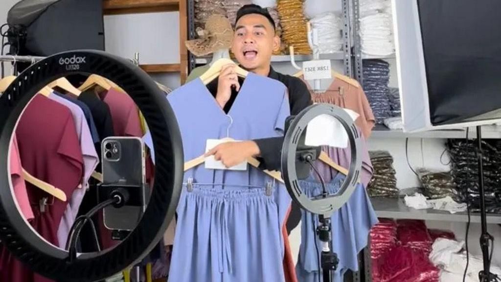 Streamer, Evo Sya, holding a blue summer dress while filming his live stream